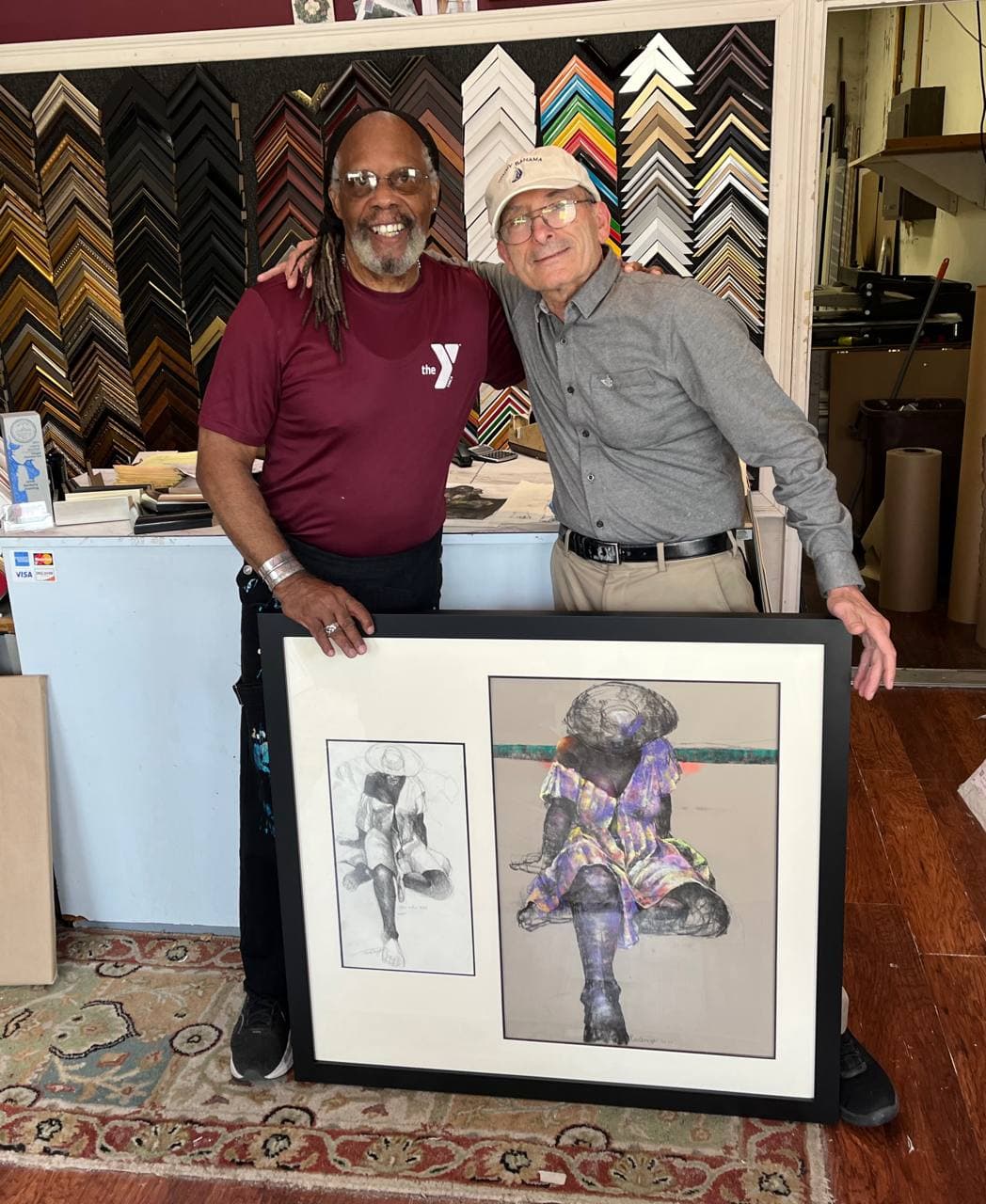 Paul Goodnight and West Roxbury Framing owner Moses Hasson holding a double-opening frame with two of Goodnight's seated figure drawings