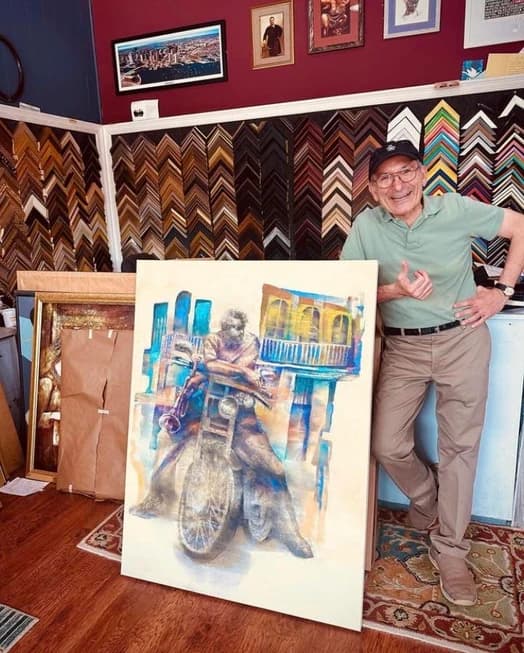 Framer standing next to large framed artwork in shop